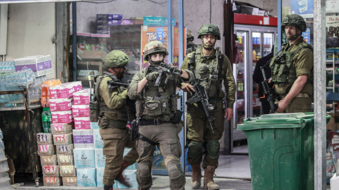 Israeli occupation forces search shops near the site of the stabbing attack at the Shavei Shomron checkpoint, west of the city of Nablus in the occupied West Bank. 