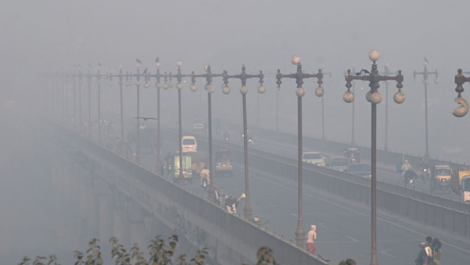 Commuters ride along a street engulfed in smog in Lahore on 18 November 2024