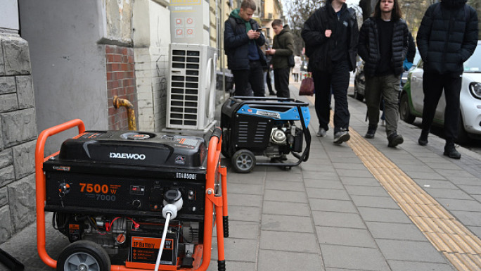 Local residents walk past electric generators supplying electricity to a cafe during a power outage in Lviv on November 28, 2024, amid the Russian invasion of Ukraine. More than a million Ukrainians were left without power in freezing cold temperatures on November 28, 2024 after a massive nationwide Russian missile and drone attack. 	