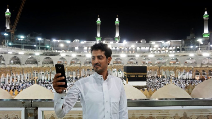 A man on hajj taking a selfie while at Mecca's Great Mosque