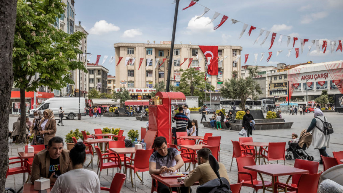 People sit in a cafe and walk on the streets in a square in Esenyurt, a socially diverse district in western Istanbul