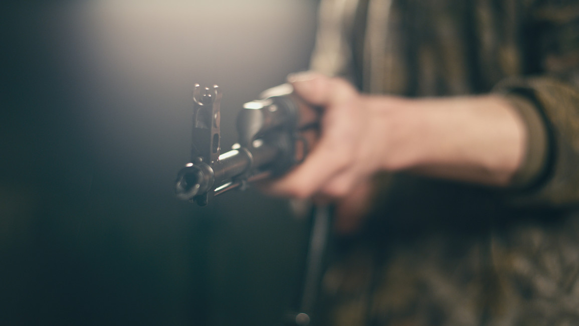 Professional shooter aiming machine gun towards camera