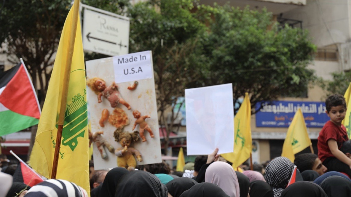 Demonstrators wave Palestinian and Hezbollah flags in the southern suburbs of Beirut in protest of Israel's strike on Baptist hospital on 17 October, which left at least 471 dead. [William Christou - TNA].