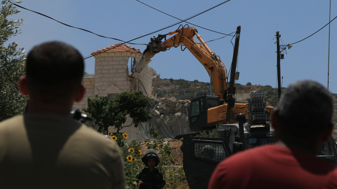 Palestinian residents in the village of Jalbun, east of Jenin in the occupied West Bank, look on as Israeli forces demolish two homes. [Shatha Hanaysha/TNA] 