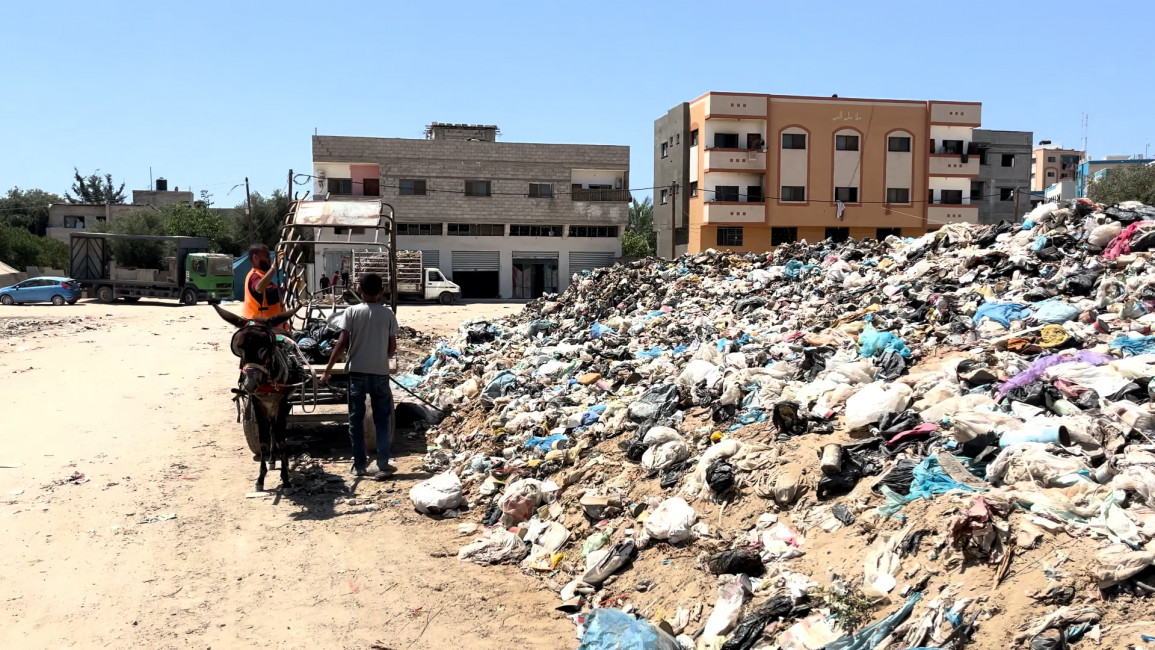 Piles of rubbish with two workers standing closeby