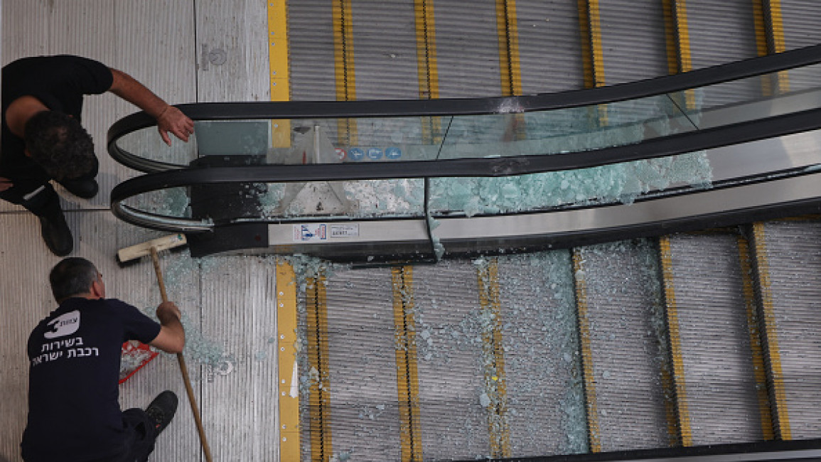 Employees sweep shards of glass from an escalator reportedly damaged after a missile was fired from Yemen, inside a train station in the Israeli town of Modin on September 15, 2024.