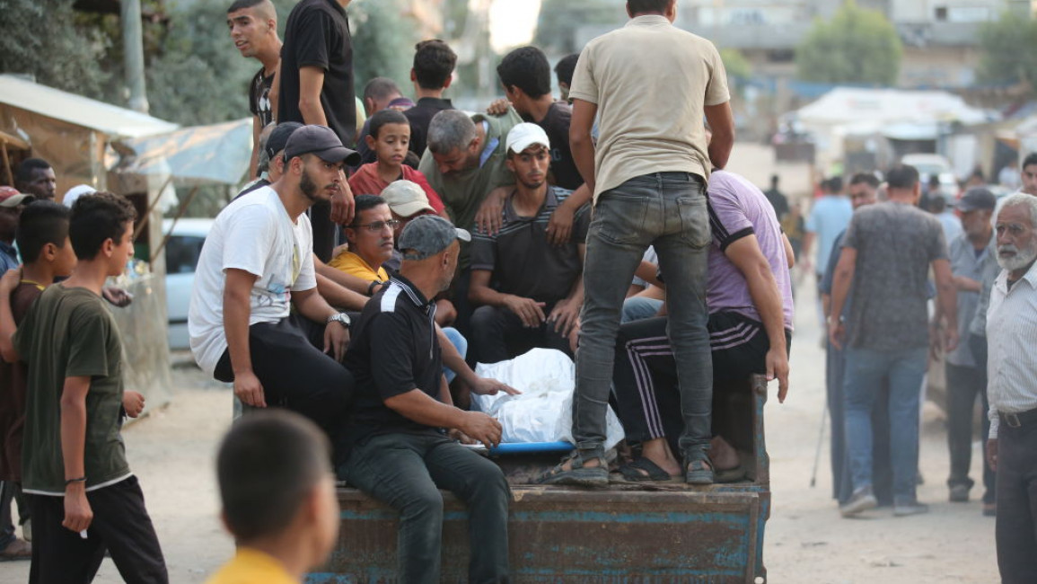 Displaced Palestinians in Gaza on board a trailer with a body.