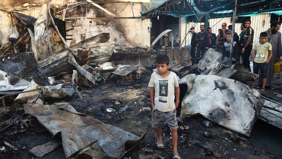 Palestinian boy walks past debris as people check the destruction following an Israeli strike around tents for displaced people inside the walls of Al-Aqsa Martyrs Hospital in Deir al-Balah, Gaza Strip, October 14, 2024 (EYAD BABA/AFP via Getty)