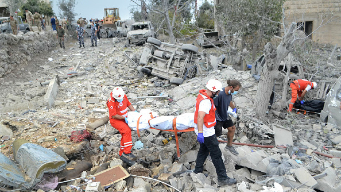 Paramedics with the Lebanese Red Cross transport a body unearthed from the rubble at the site of an Israeli airstrike that targeted the northern Lebanese village of Aito on October 14, 2024. (Photo by FATHI AL-MASRI/AFP via Getty Images)