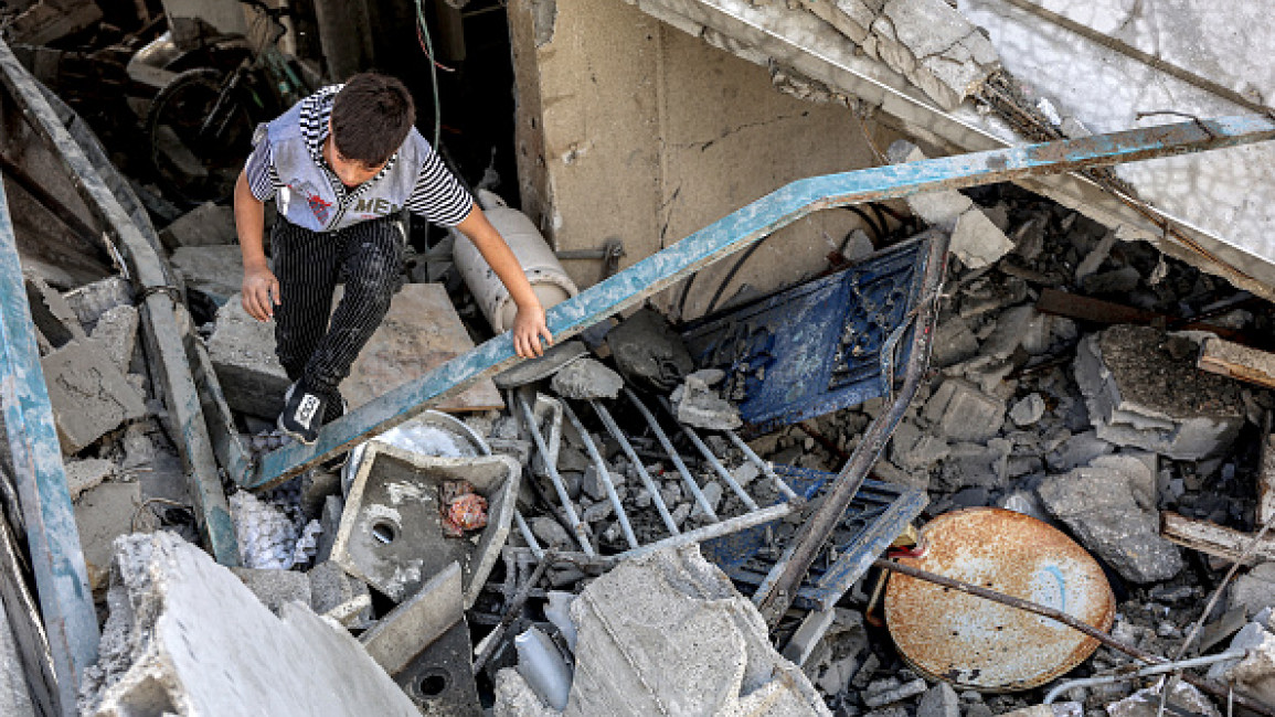 A boy climbs through the rubble of a collapsed building following Israeli bombardment in the Saftawi district in Jabalia in the northern Gaza Strip on October 15, 2024