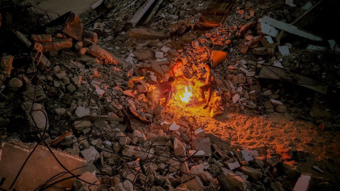 A fire burns over the rubble of a destroyed home in Khan Younis