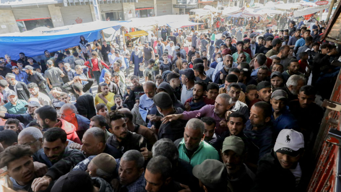 Displaced Palestinians queue to buy bread from a bakery in Deir Al-Balah in the central Gaza Strip