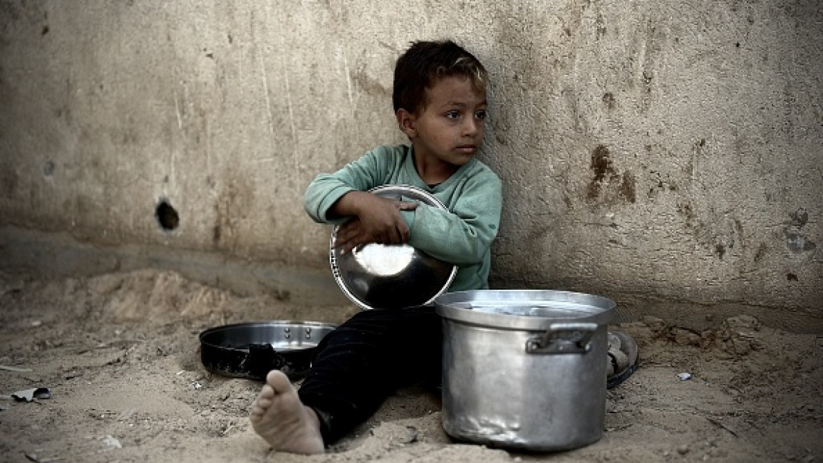 Palestinian child is seen with a pot as he waits to receive the food distributed by charitable organizations to those who fled the Israeli army attacks and took refuge in Khan Yunis, Gaza on October 28, 2024. 