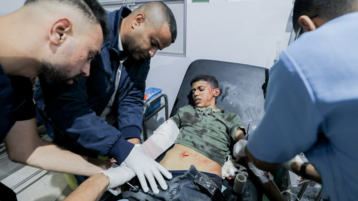 Doctors examine a young patient in a hospital bed at Al-Awda Hospital in Al-Nuseirat, Gaza, on October 28, 2024.