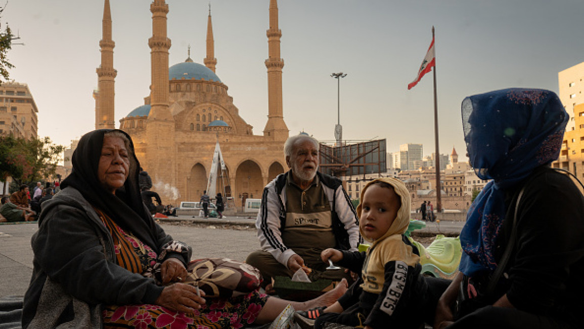 A family is seen sitting on a blanket which they call their...