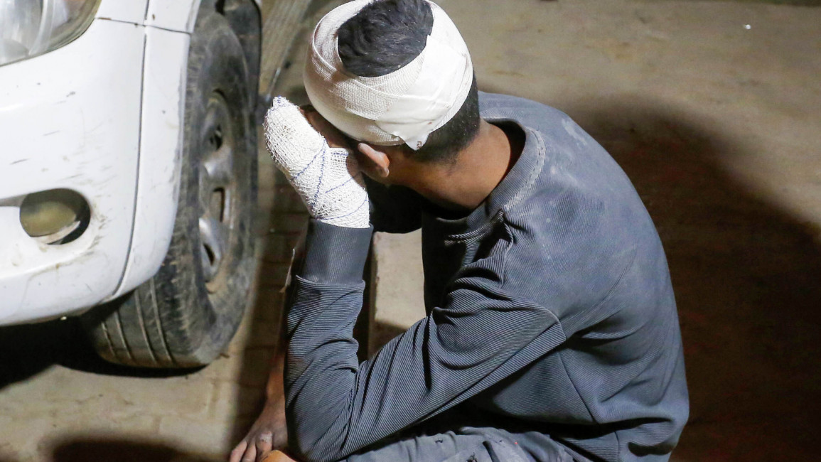 An injured Palestinian sits on a concrete pavement following receiving a medical treatment as Palestinians, who lost their lives after Israeli attacks hit Nuseirat refugee camp, Az-Zawayda and Deir Al-Balah, are brought to the al-Aqsa Martyrs Hospital in Deir Al Balah, 