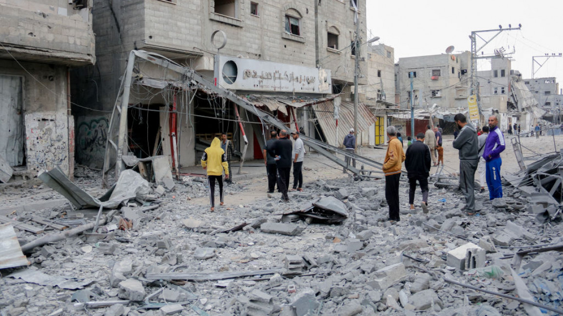 Residents walk through the rubble in the Al-Zawaida area of the Gaza Strip on 1 November 2024, following an Israeli airstrike