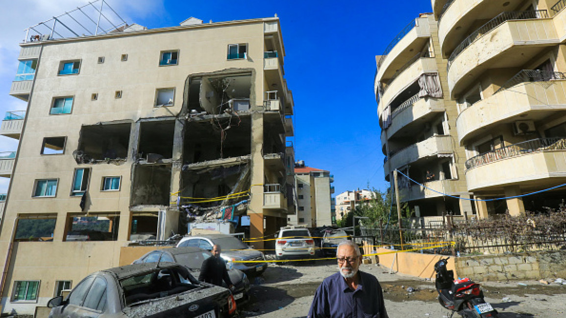 Residents walk past damaged cars in front of an apartment destroyed in an Israeli strike in the Dawhet Aramoun area, south of Beirut, on November 13, 2024, amid the ongoing war between Israel and Hezbollah. (AFP via Getty Images)