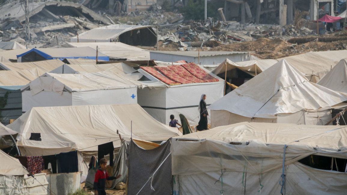 People walk among rows of makeshift tents in Al-Bureij refugee camp, central Gaza Strip