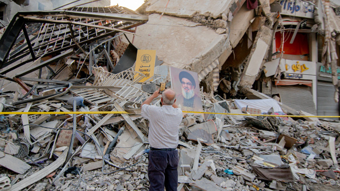 A man photographs the debris as the photo of the former Hezbollah chief Hassan Nasrallah is placed on buildings that were demolished in Israeli airstrikes south of Beirut on November 14, 2024. (FADEL ITANI/Middle East Images/AFP via Getty Images)