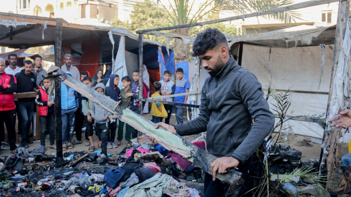 A young man examines the remains of belongings amidst the rubble of displacement tents west of Deir al-Balah