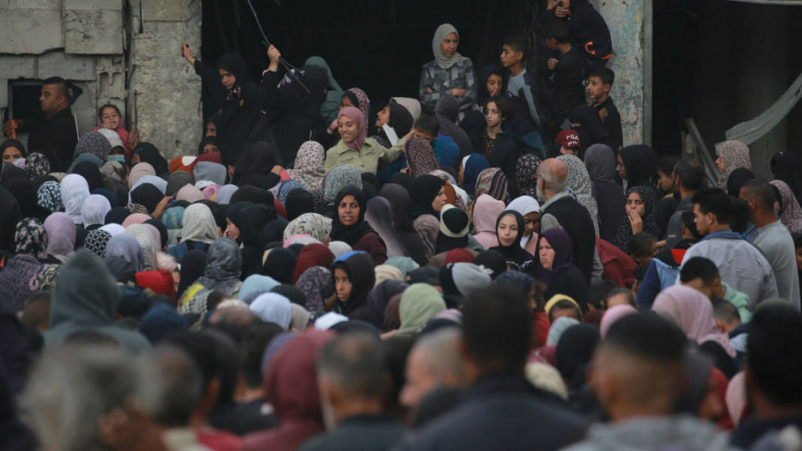 Palestinians wait in a queue to receive bread outside a bakery in Khan Younis